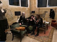 three women sitting on a couch in a room with guitars and other items around them