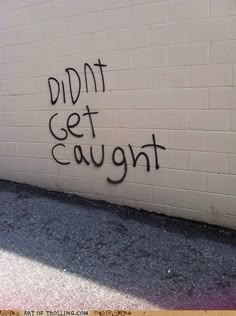 graffiti is spray painted on the side of a white brick wall that reads, didn't get caught