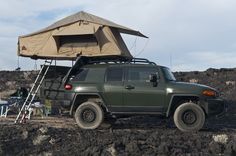 a green jeep with a tent on top of it