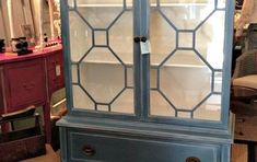 an old china cabinet with glass doors and drawers in a room full of furniture items