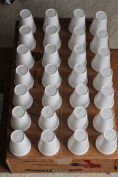 a box filled with white cups sitting on top of a carpeted floor next to each other