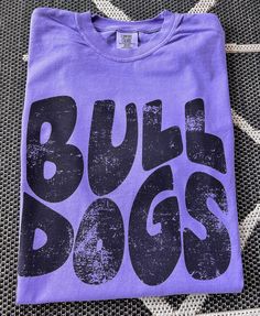 Here's a tee made just for you and your team spirit! This distressed BULLDOGS Mascot tee is super soft and comfy. Shown on a super soft comfort colors VIOLET tee, but so many colors to choose from. Design made on unisex comfort colors shirt. Casual Purple T-shirt For Fan Merchandise, Casual Purple T-shirt For Fans, Cotton T-shirt With Logo Print For Sports Season, Soft-washed Cotton T-shirt For Fan Apparel, Soft-washed Cotton T-shirt For Fans, Purple Crew Neck T-shirt For School Spirit, Collegiate Soft-washed Tops For Streetwear, Collegiate Style Soft-washed Tops For Streetwear, Purple Fan Apparel T-shirt With Letter Print