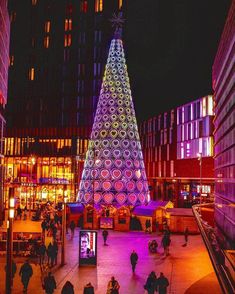 a brightly lit christmas tree in the middle of a city