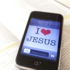 an iphone with the word i love jesus on it sitting next to an open book