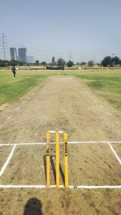 a baseball field that has some yellow poles in the dirt and grass near it,