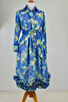 This sheer blue wrinkle reistant fabric is brought to life with abstact flowers in summer colors. The two piece dress has a matching tie belt and polyester accordion pleated and wired ruffled hemline. The top has a tailored blouse design with shell button down front. The blouse is not lined, the skirt has a white cotton blend lining. Skirt closes with hooks,eyes, and nylon zipper. ROMANTIC, FEMININE WRINKLE RESISTANT so GREAT CHOICE FOR EVENINGS OUT, PARTIES, TRAVEL, RESORTDUST OFF YOUR WHITE SA 1970s Style Silk Dresses For Spring, 1970s Style Blue Floral Print Dresses, Tailored Blouse, Blue Gown, Tie Dress, Two Piece Dress, Blouse Design, Summer Colors, Piece Dress