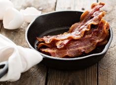 bacon in a frying pan on a wooden table