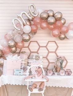 a baby sitting in a chair next to a table with balloons and presents on it