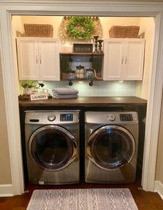 a washer and dryer in a small room with white cupboards on the wall