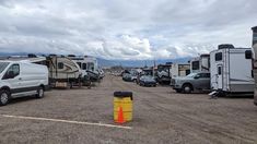 an rv park filled with lots of parked cars and motorhomes under cloudy skies