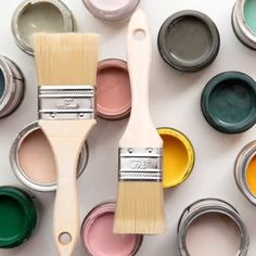 several paint cans with different colors of paint on them and one brush in the middle