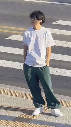 a man standing on the side of a road next to a cross walk with his hands in his pockets