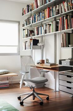 a white chair sitting in front of a book shelf filled with lots of books on it