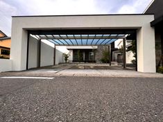 an empty parking lot in front of a white building with a glass roof and door