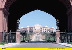 an entrance to a large building with a fountain in the center and fence surrounding it