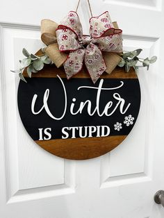 "Winter is stupid front door sign with cutout raised letters. Size- 15\", 18\", 20\", 22\", 24' Each sign includes bow and greenery. We recommend fluffing your bow after it arrives! These beautiful wood hanging monograms are cut from high-quality, 1/4\" birch.  This will make the perfect gift for friends and family, or a great addition to your home. Each one is hand made by our family for yours. We take the time and care to make sure it is arrives to you perfect and in a timely manner. Your 100% Winter Door Rounds, Round Signs For The Home, Simple Winter Door Hangers, Winter Front Door Sign, Round Winter Door Hangers, Wood Rounds Door Hanger Winter, Round Door Signs For Winter, Cricut Winter Door Sign