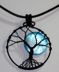 a tree of life pendant with a blue stone in the center on a black cord