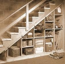 the stairs are open and neatly organized in this garage storage area with baskets, boxes, and other items