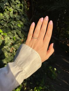 a woman's hand with a ring on her left wrist and green plants in the background