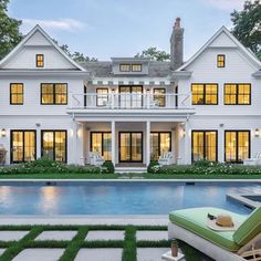 a large white house sitting next to a swimming pool in front of a lush green lawn