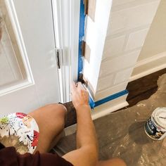 a man is painting the inside of a door with white paint and brown paper on it