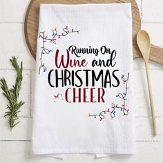 a white towel with the words running one wine and christmas cheer on it next to a wooden spoon