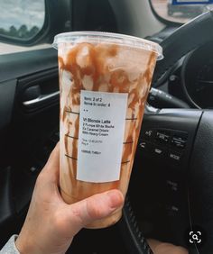 a person holding up a cup of iced coffee in their hand with information on it