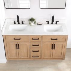 two sinks in a bathroom with mirrors on the wall above them and wood cabinets below