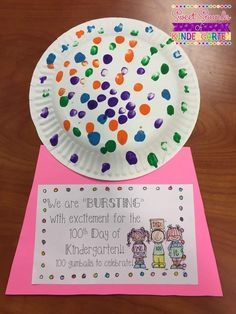 a paper plate with colorful confetti on it sitting next to a pink card