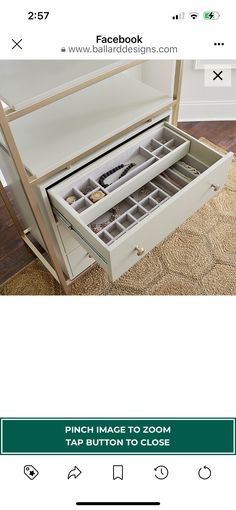 an open drawer on the floor in front of a white table with drawers underneath it