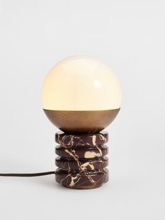 a table lamp that is sitting on top of some stacked rocks and has a white light in the middle