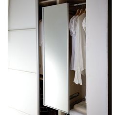 an open closet with clothes on hangers and shoes in the bottom drawer, next to a mirror