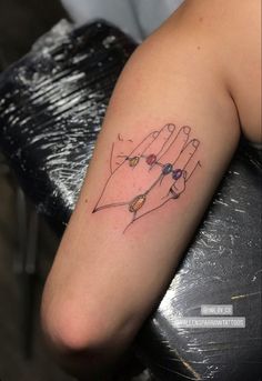 a woman's arm with a tattoo on it that has an image of two hands holding