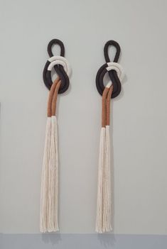 two black, white and brown wall hangings with tassels on the ends