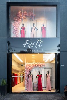 a store front with mannequins dressed in pink and red dresses on display