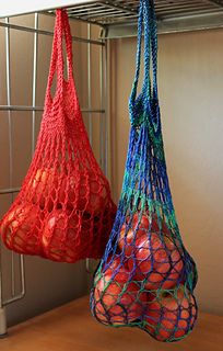 two bags of fruit are hanging from a rack