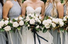 the bridesmaids are holding their bouquets with white roses and greenery on them