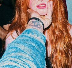 a woman with long red hair and tattoos on her arm is looking at the camera