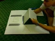 a man is cutting out the letter b from a piece of construction paper with scissors