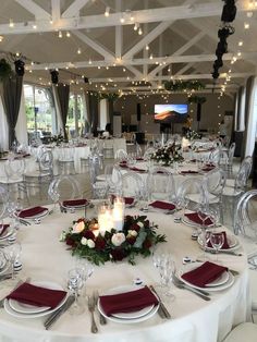 a table set up for an event with white linens, red napkins and silverware