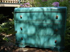 a blue dresser sitting in the middle of a garden