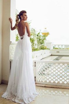 a woman in a white wedding dress standing on a balcony with her back to the camera