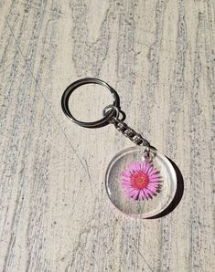 a glass keychain with a pink flower on it