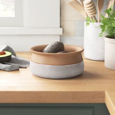 an avocado is sitting in a bowl on the counter next to some utensils