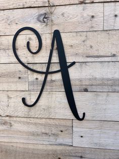 a metal letter mounted to the side of a wooden wall with an initial on it