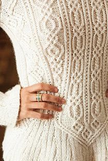 a close up of a person wearing a sweater with rings on their fingers and holding onto the arm of another person's hand