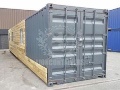 a large gray shipping container sitting on top of a parking lot next to blue containers