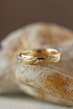 two gold wedding rings sitting on top of a rock