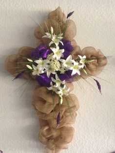 a cross made out of tulle and flowers hanging on the side of a wall