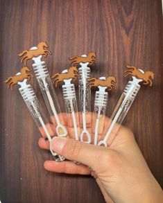 a person is holding six plastic toothbrushes with horses on them in front of a wooden background